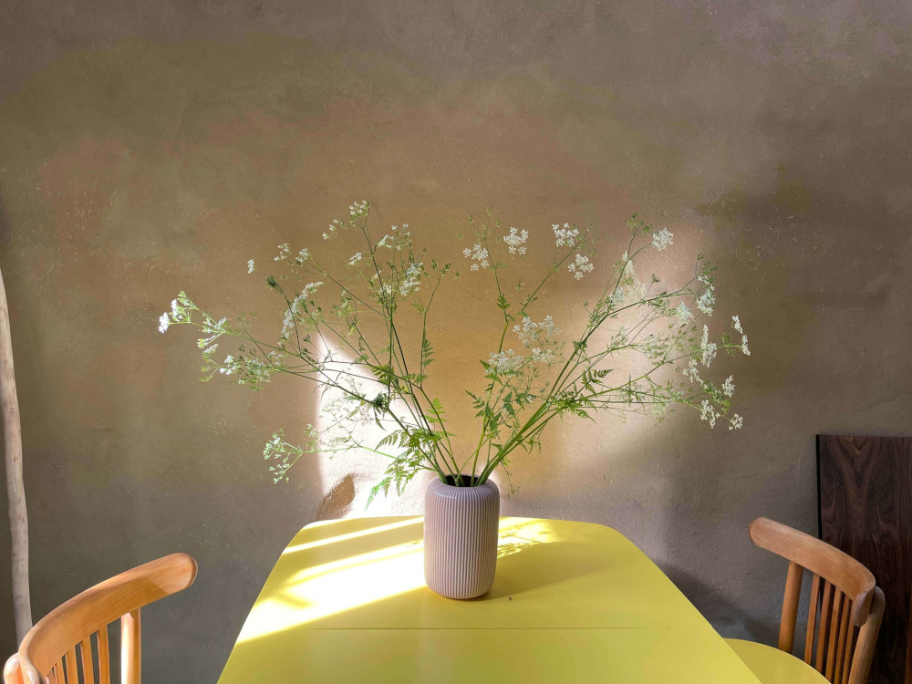 Gele tafel met bloemen in vaas